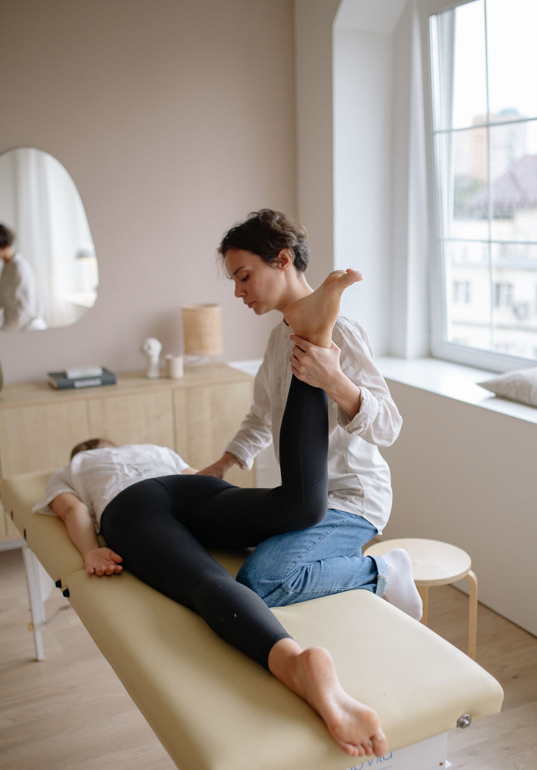 Une physiothérapeute mobilise la jambe d’une patiente pendant une séance